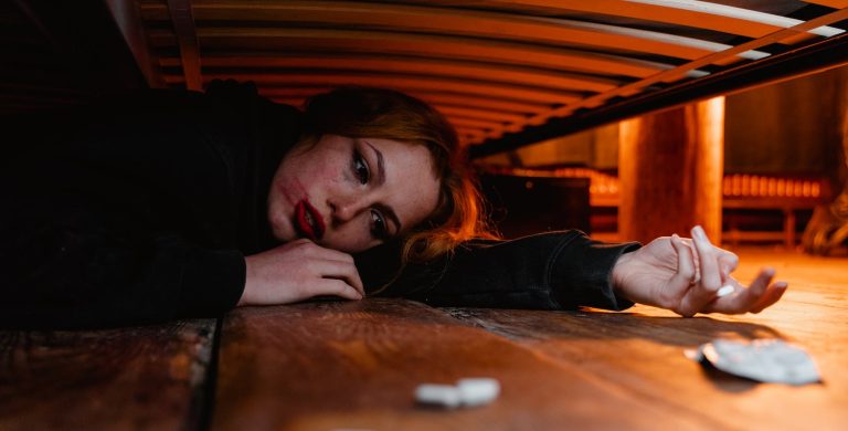 an emotional woman lying under the bed